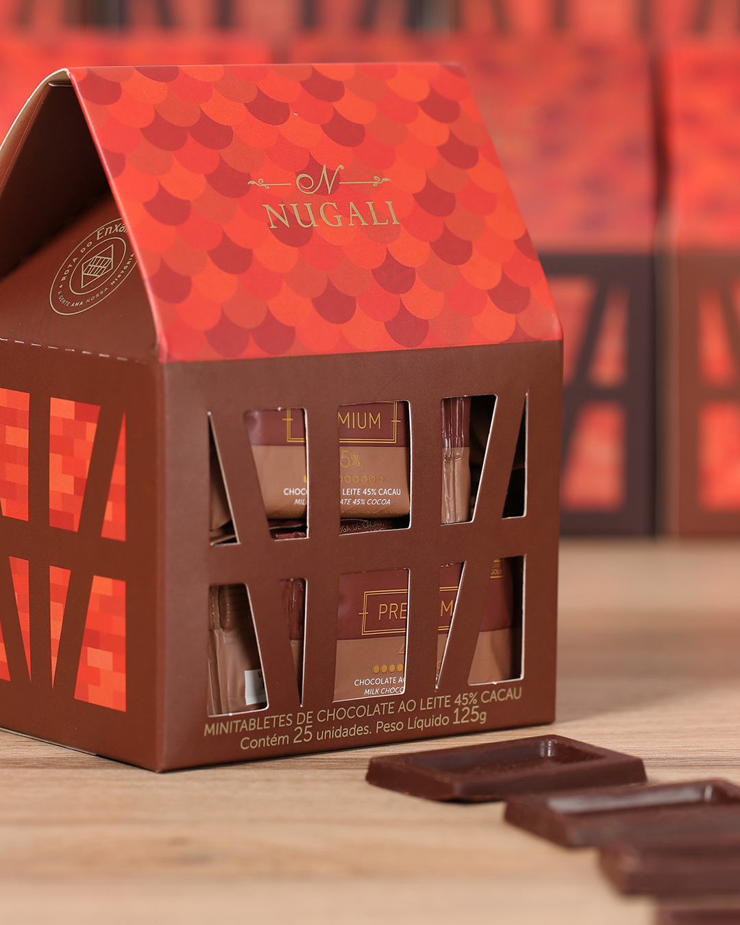 Caixinha Enxaimel Nugali, 25 mini tabletes de Chocolate ao Leite 45% Cacau, irresistivelmente cremosos e premiados, em embalagem inspirada em casas enxaimel, perfeita para encantar e presentear.