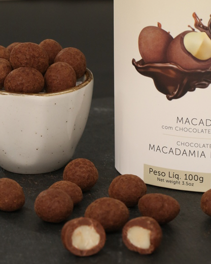 Dragée de macadâmias crocantes envolvidas em chocolate ao leite, destacando sua textura irresistível e brilho natural, símbolo de dragée saudável e gourmet”