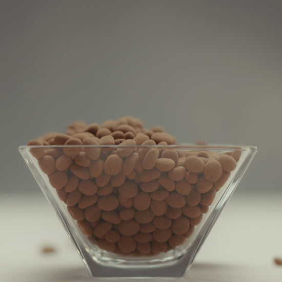 Dragée de nibs de cacau coberto com chocolate ao leite, premiado, feito com ingredientes selecionados de alta qualidade, ideal para quem aprecia chocolates gourmet.